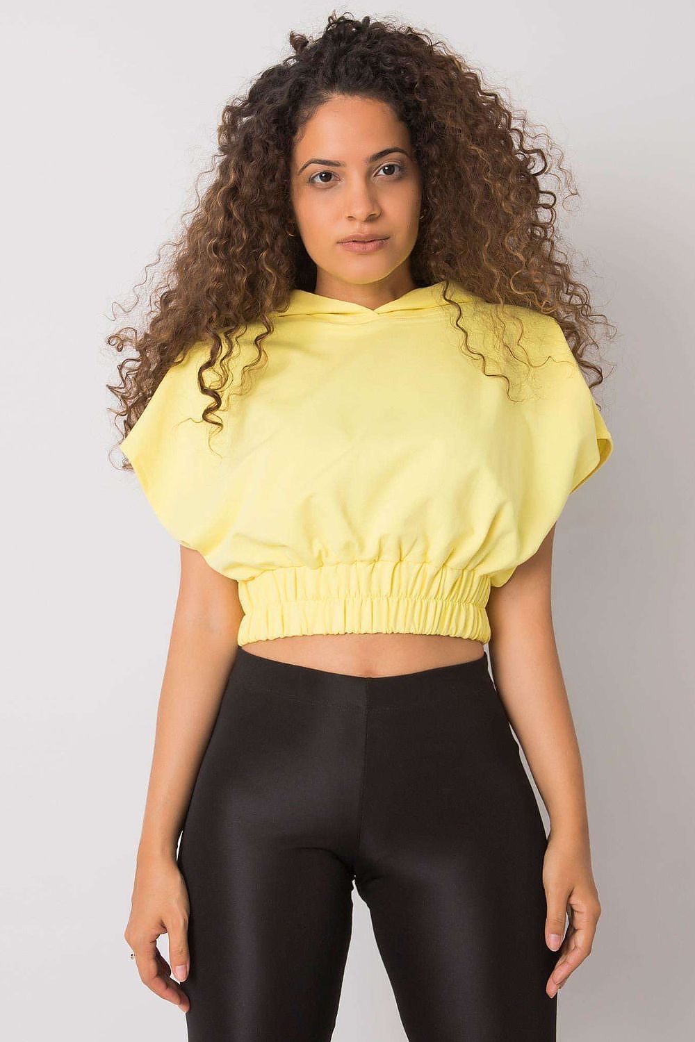 Close-up of a model wearing a Ladies' Loose-Fit Sweatshirt with Short Sleeves and Hood in yellow, highlighting its luxurious design and relaxed fit.