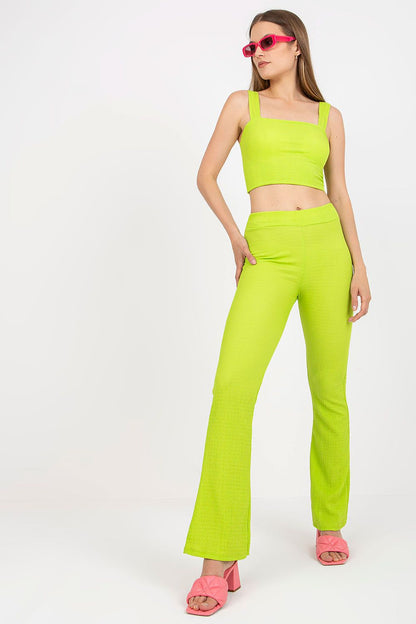 Italy Moda Women's Elegant Two-Piece Set in striking lime green, model confidently posing in short top with padded cups and high-waisted wide-leg pants, accented with pink accessories.