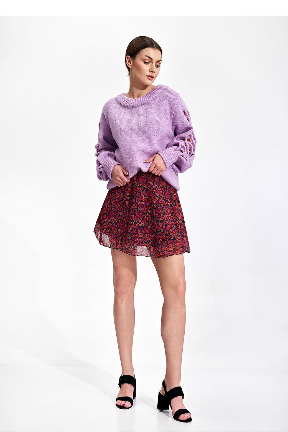 Chic model displaying the Flared Mini Skirt by Figl, featuring a flared design in a vibrant floral pattern, styled with a relaxed lavender sweater.