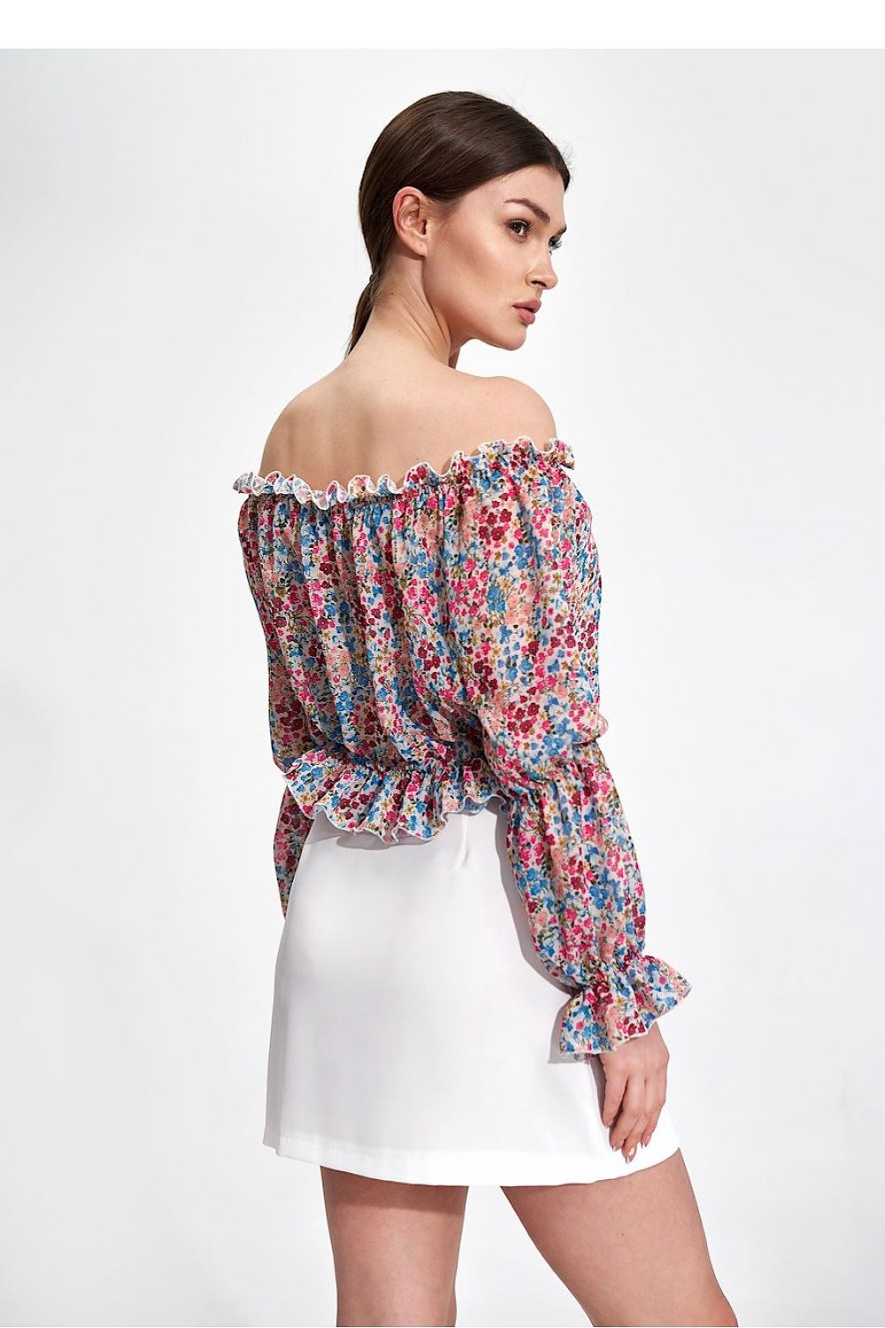 Elegantly Airy Figl Long Sleeve Blouse with Elastic Bands - Back view of a model wearing a floral blouse with ruffled sleeves, combined with a chic white skirt.