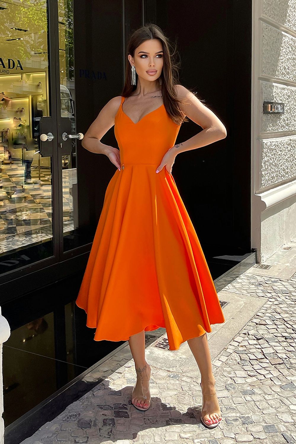 Elegant Bicotone Midi Dress with Shoulder Straps, Flared Skirt and Exposed Back - Model showcasing the vibrant orange midi dress in an upscale urban setting, highlighting its chic design and luxurious fabric.