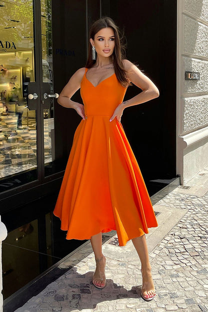 Elegant Bicotone Midi Dress with Shoulder Straps, Flared Skirt and Exposed Back - Model showcasing the vibrant orange midi dress in an upscale urban setting, highlighting its chic design and luxurious fabric.