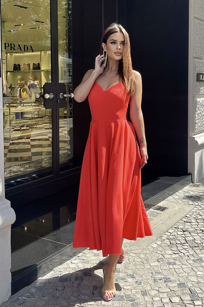 An elegant Bicotone midi dress with shoulder straps and a flared skirt, worn by a stylish model outside a luxury store, showcasing a chic and feminine look.