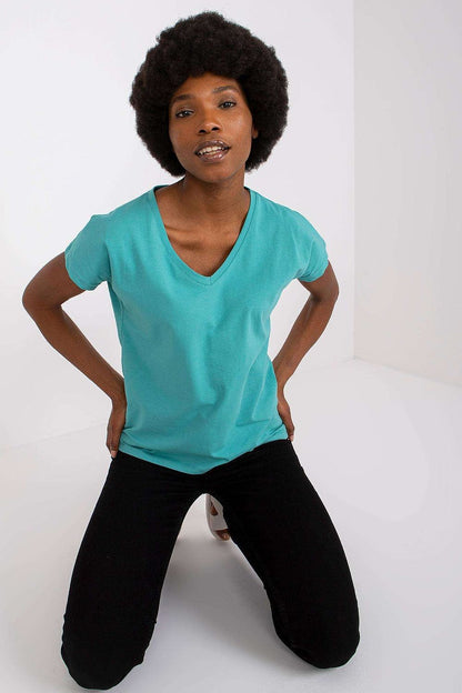 Model kneeling in a Luxury BFG Heart Neckline T-Shirt, displaying a stylish design in a vibrant turquoise colour, perfect for casual wear.