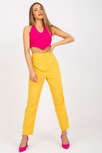 Stylish model posing in luxurious yellow Xsapienza Women’s High-Waisted Straight Cut Trousers with Imitation Pockets, perfect for styling, complemented by a vibrant pink top.