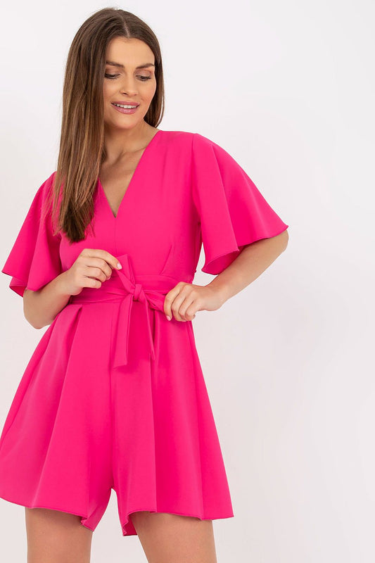 Elegant Rue Paris Jumpsuit With Cheeky Neckline And Tied Waist, showcased by a model with long hair, wearing the vibrant pink jumpsuit that features wide short sleeves, perfect for any occasion.