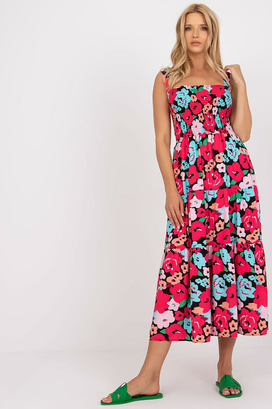 Floral Summer Dress by Rue Paris featuring wide straps and a luxurious flared frill design, modelled elegantly with vibrant floral patterns in pink and turquoise hues.