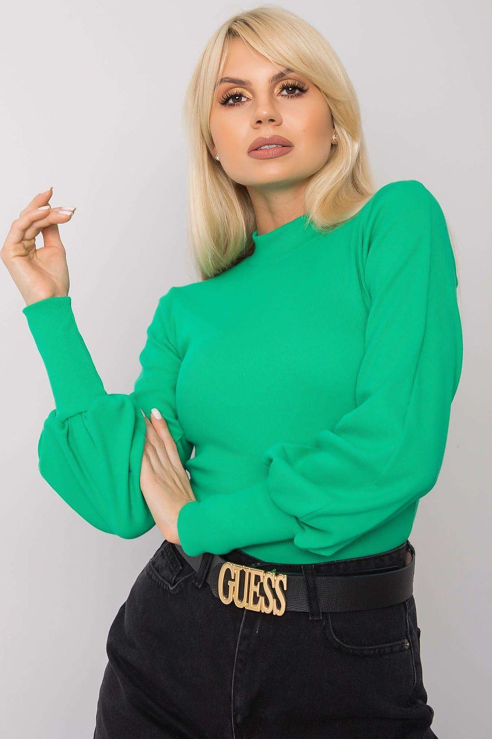 Close-up of a model in a bold green Elegant Long Sleeve Ribbed Blouse by Rue Paris, emphasising its plush cotton and spandex fabric along with its elegant ribbed cuffs.