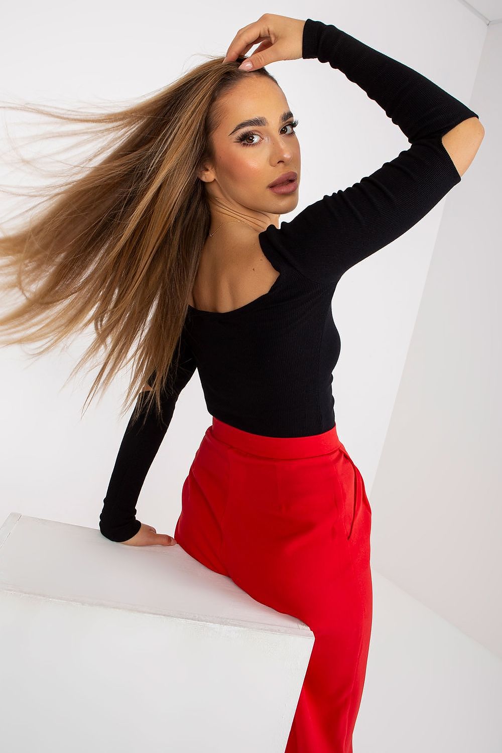 Elegant Long Sleeve Blouse with Boat Neckline and Decorative Slits - Rue Paris, model demonstrates a stylish pose showing the back and cutout of the black blouse.