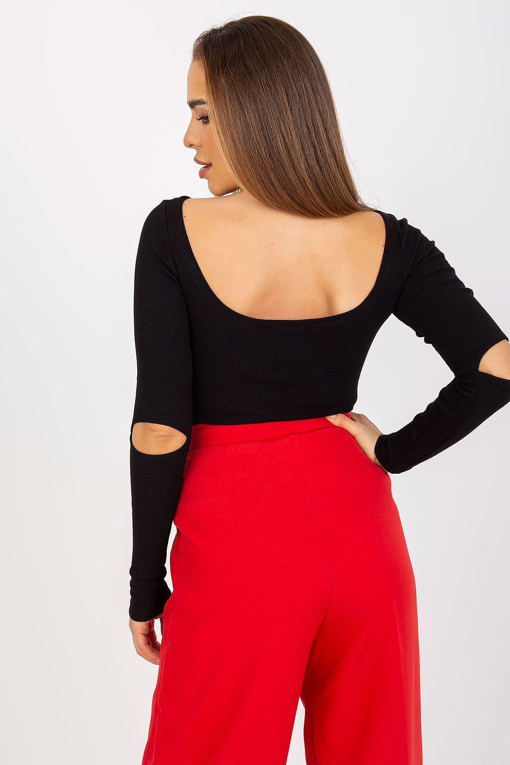 Elegant Long Sleeve Blouse with Boat Neckline and Decorative Slits - Rue Paris, model highlights the back view of the blouse with cutouts while wearing elegant red trousers.