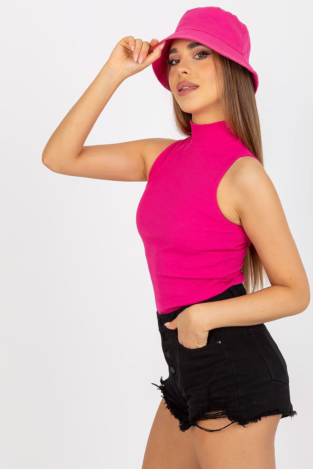 Elegant Ribbed Half Turtleneck Top by Rue Paris, featuring a modern pink hue, complemented by distressed black shorts. The model strikes a pose with grace, wearing a matching bucket hat.