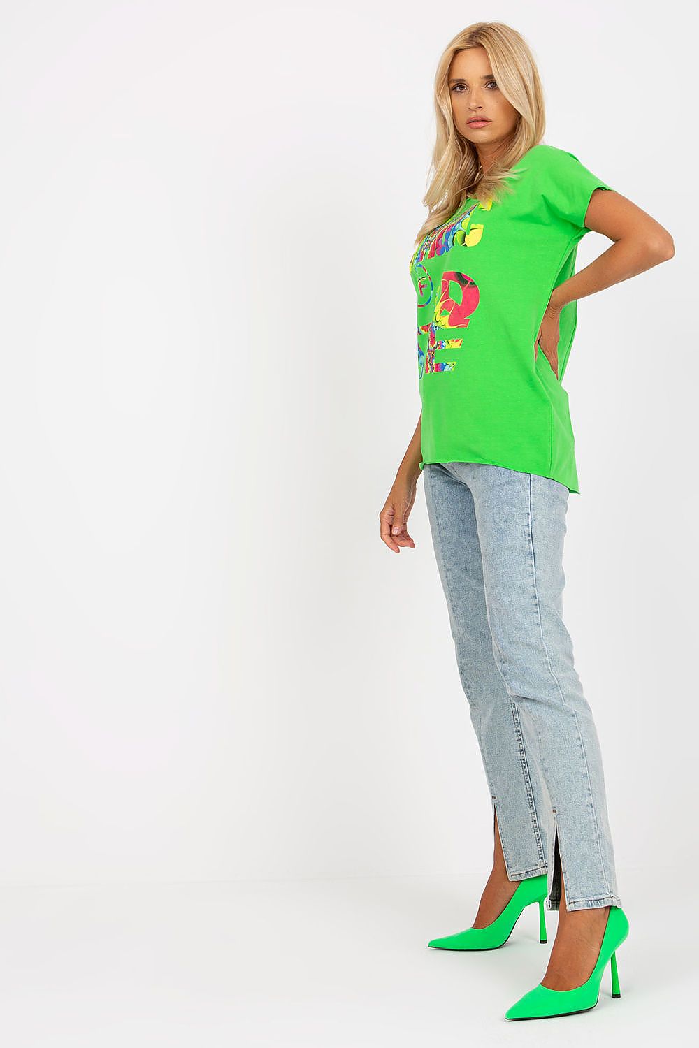 Model striking a pose in the Elegant Straight Cut Cotton Spandex Blouse with Decorative Print – Short Sleeves, EU Size 0, wearing light denim jeans and stunning green heels, embodying sophistication and elegance.