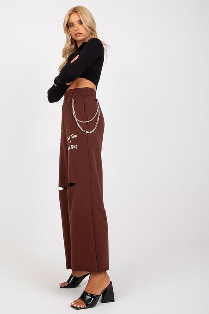 Side view of elegant model in Luxury Women's Wide Leg Sweatpants with Pockets, Elastic Waistband and Decorative Slits, showcasing a luxurious brown colour with stylish embellishments.