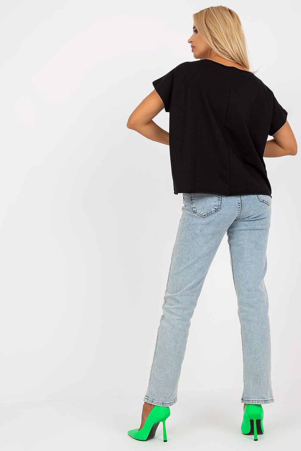 Back view of a model in a black Elegant Short-Sleeved Blouse with Embroidery, complemented by chic denim, revealing the blouse's luxurious fit and style.