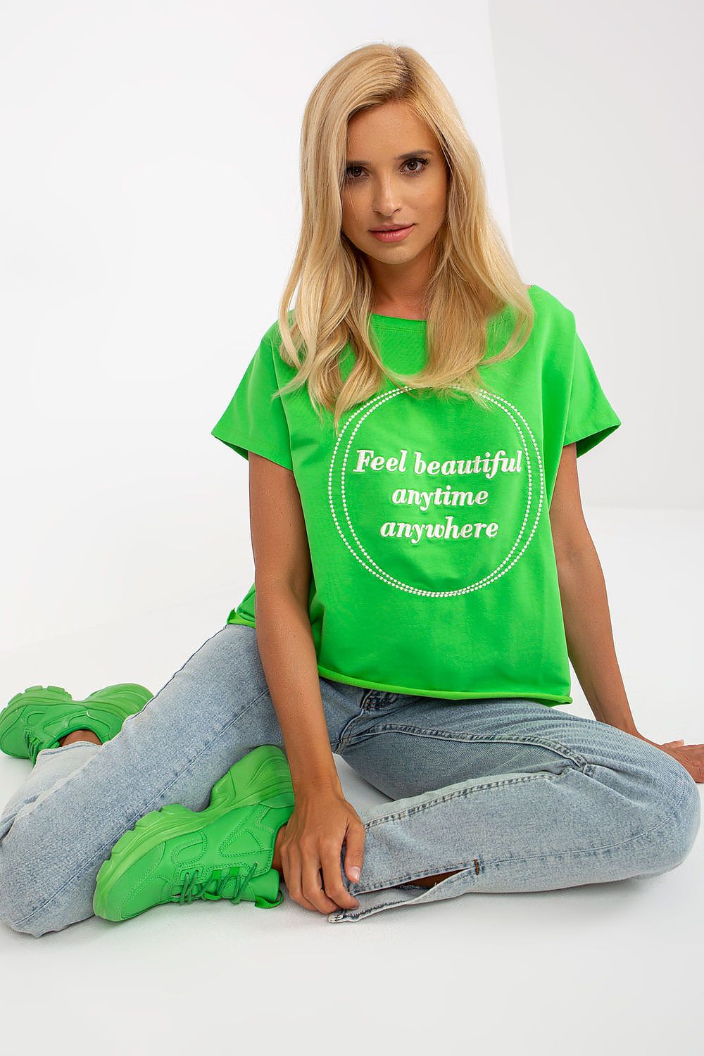 Elegant Short-Sleeved Blouse with Embroidery - Cotton and Spandex Blend, Loose Fit, a seated model displaying a green embroidered blouse styled with relaxed jeans.