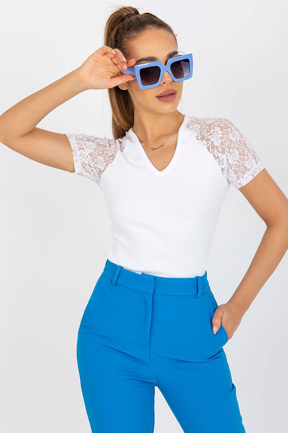 Elegant Rue Paris Blouse with Lace Short Sleeves and Heart Neckline displayed on a model wearing it in white, complemented by vibrant blue trousers, exuding modern elegance.