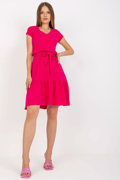 Stylish model in an Elegant Summer Dress by Rue Paris in bright pink, highlighting its flared design, v-neckline, and waist tie.