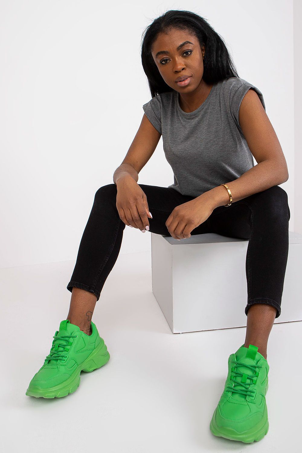 Women's Luxurious BFG Cotton Spandex T-Shirt - Short Sleeve Round Neckline, Perfect Fit. Model sitting confidently in a grey t-shirt, paired with bright green sneakers.