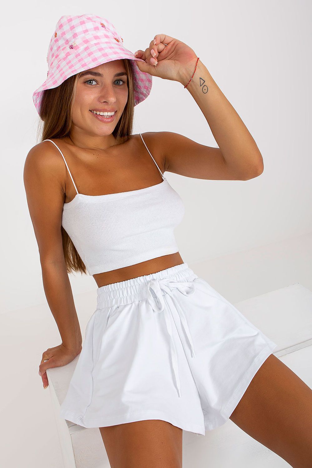 Elegant Women's Wide Leg Shorts by Rue Paris in white, styled with a chic white crop top and a pink checkered bucket hat, showcasing a relaxed and sophisticated summer look.