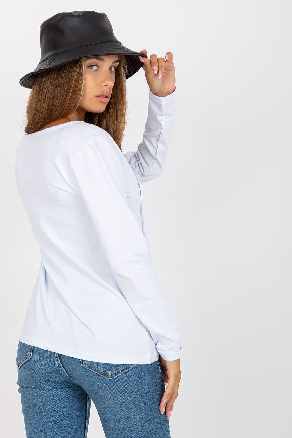 Elegant Long Sleeve Blouse By Rue Paris With Deep Neckline And Binding Detail, back view of a model in a white long sleeve blouse, highlighting the binding detail while holding a black bucket hat.