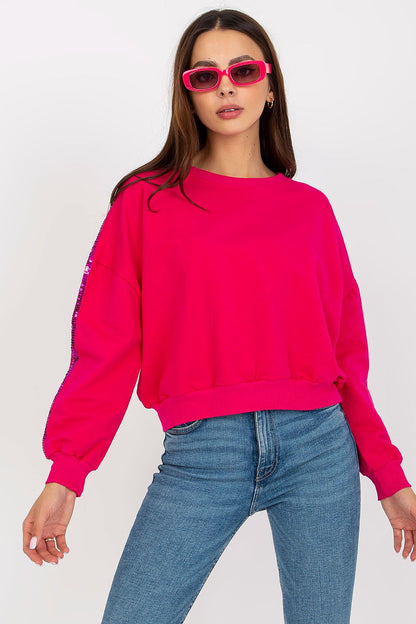 Luxury Rue Paris Women's Sequined Long Sleeve Sweatshirt with Round Neckline - Elegant Comfort, featuring a vibrant pink design, model wears with trendy sunglasses against a plain background.