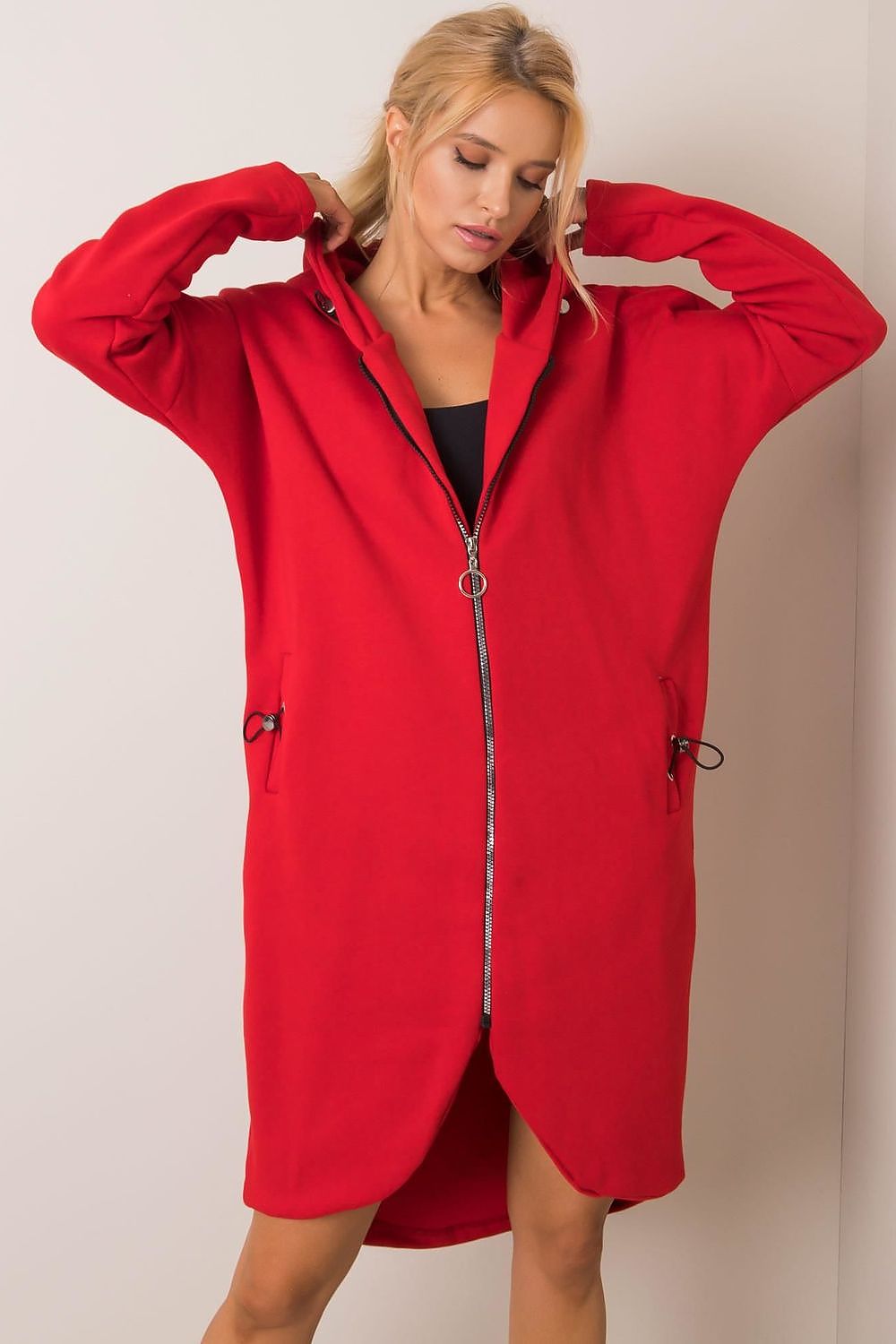 Model in striking red Rue Paris Zip-Up Extended Cut Sweatshirt with Hood and Side Pockets, embodying comfort and style in a vibrant hue for a fashionable statement.