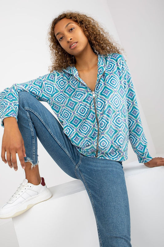 Luxury Rue Paris Women's Zippered Sweatshirt with Hood and Long Sleeves, featuring elegant geometric patterns, styled with distressed jeans and chic white sneakers.