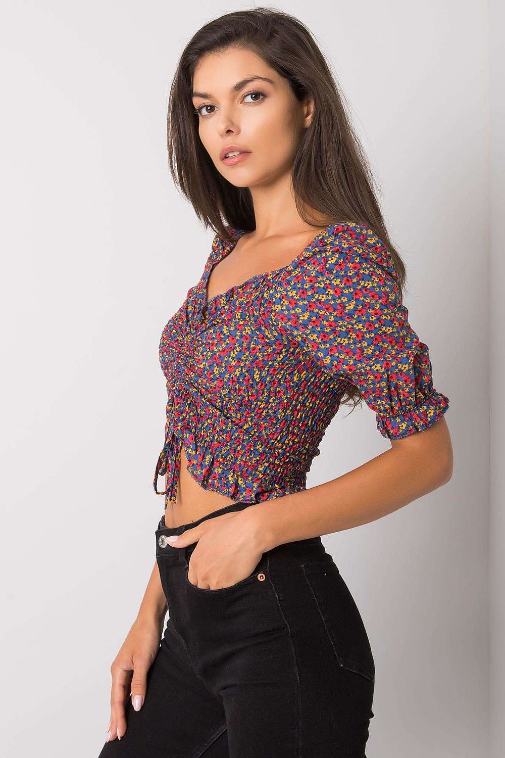 Elegant fitted short sleeve V-neck blouse by Rue Paris, showcasing a chic floral design, accentuated by gathered detailing, paired effortlessly with black trousers for a luxurious casual look.