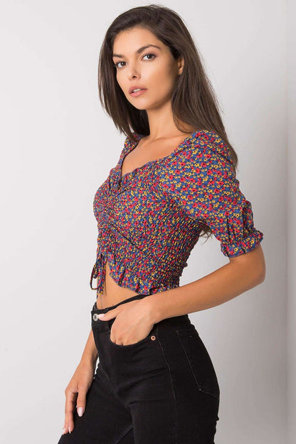 Elegant fitted short sleeve V-neck blouse by Rue Paris, showcasing a chic floral design, accentuated by gathered detailing, paired effortlessly with black trousers for a luxurious casual look.