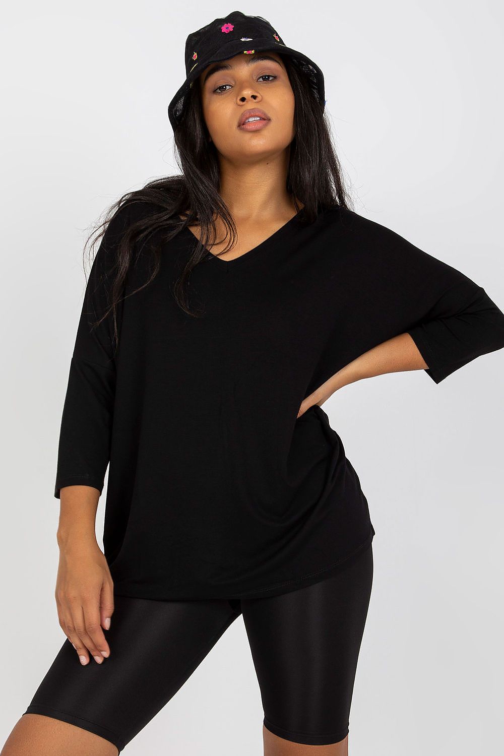 Elegant Plus Size Blouse With 3/4 Sleeves And Sweetheart Neckline, featuring a model in a black top, styled with a fashionable bucket hat and black leggings.