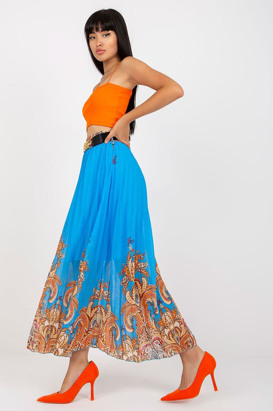 Elegant long skirt with elastic waistband and a decorative chain belt by Italy Moda, model in a side pose highlighting the flowing design of the blue skirt with elegant patterns against a chic orange crop top.