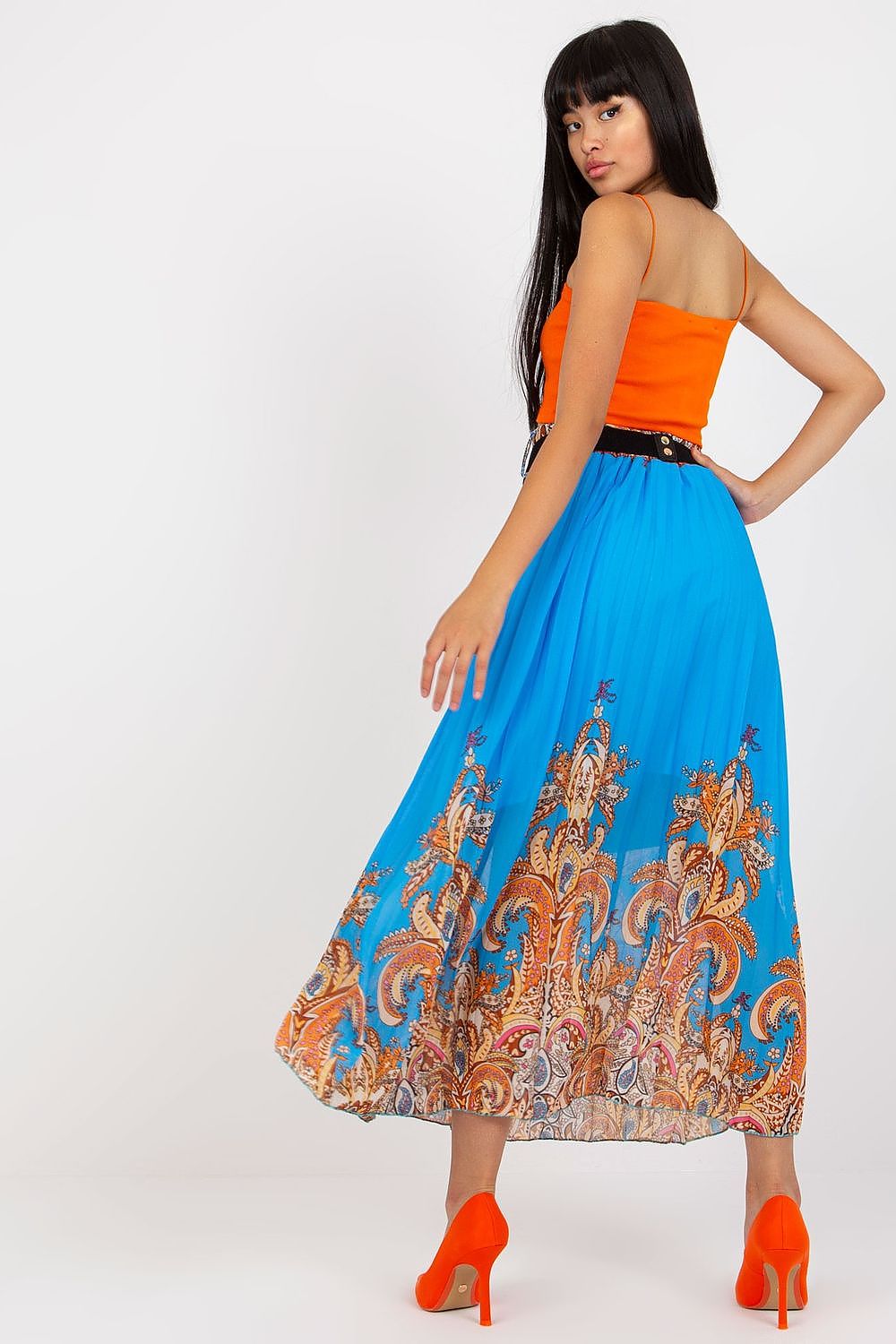 Elegant long skirt with elastic waistband and a decorative chain belt by Italy Moda, model presenting a graceful back view of the blue skirt featuring decorative patterns, paired with a vibrant orange crop top.