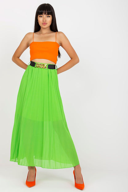 Elegant long skirt with elastic waistband and a decorative chain belt by Italy Moda, model standing confidently in a striking green skirt, showcasing the luxurious design complemented by an orange crop top and chic heels.