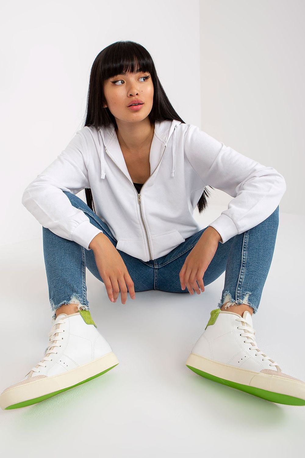 Experience the luxury of the Women’s Luxury Hooded Zippered Sweatshirt with Front Pockets - BFG, artfully styled in white, paired with trendy jeans for an effortless chic.