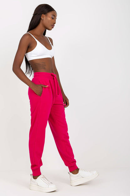 Stylish model poses in side profile wearing BFG High-Waisted Tracksuit Trousers with Elastic Waistband and Side Slip Pockets in striking pink, accentuating the relaxed yet fashionable silhouette.
