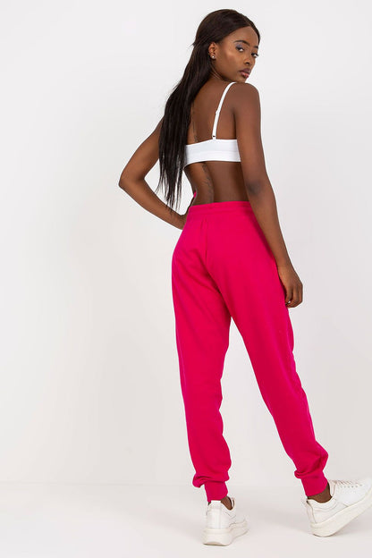 Model elegantly turns away to showcase the back view of BFG High-Waisted Tracksuit Trousers with Elastic Waistband and Side Slip Pockets in bold pink, perfectly complementing a fashionable top.