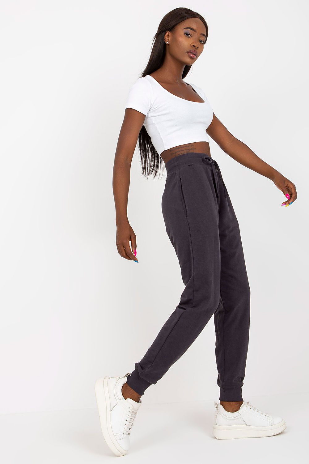 BFG High-Waisted Tracksuit Trousers with Elastic Waistband and Side Slip Pockets showcased on a model wearing a white crop top, posing elegantly, with stylish white sneakers and highlighting the sophisticated fit of the trousers in a dark tone.