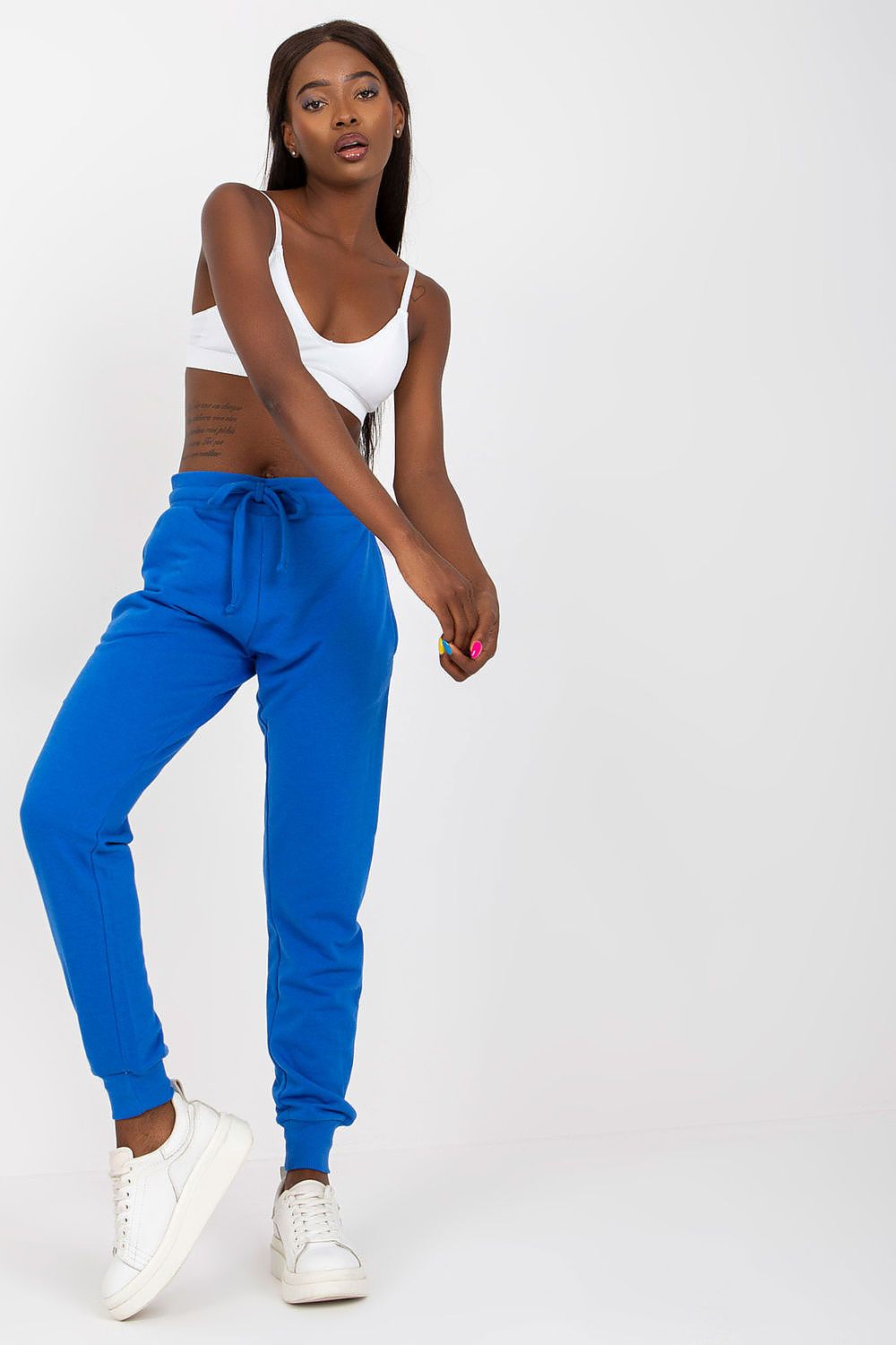 BFG High-Waisted Tracksuit Trousers with Elastic Waistband and Side Slip Pockets displayed on a model in a striking blue hue, paired with a minimalistic white crop top and white sneakers, embodying luxury in casual wear.
