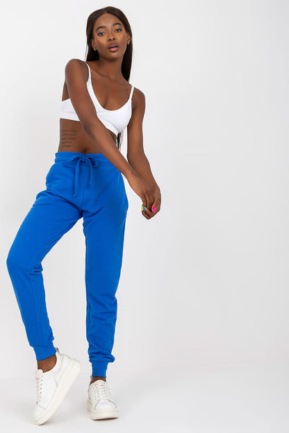 BFG High-Waisted Tracksuit Trousers with Elastic Waistband and Side Slip Pockets displayed on a model in a striking blue hue, paired with a minimalistic white crop top and white sneakers, embodying luxury in casual wear.