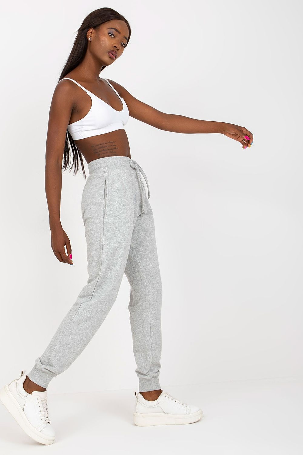 Elegant side view of BFG High-Waisted Tracksuit Trousers featuring an elastic waistband and side slip pockets, worn with a white crop top, exuding chic comfort.