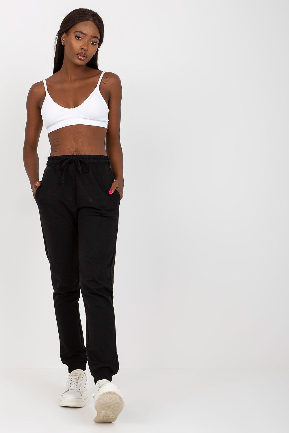 Model exuding confidence in BFG High-Waisted Sweatpants with Elastic Waistband and Side Pockets, paired with a sleek white top, perfect for luxe casual wear.