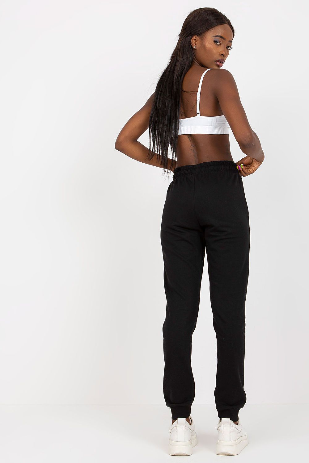 High-waisted BFG sweatpants with elastic waistband and side pockets, elegantly worn by a model showcasing the rear view in a minimalist setting.