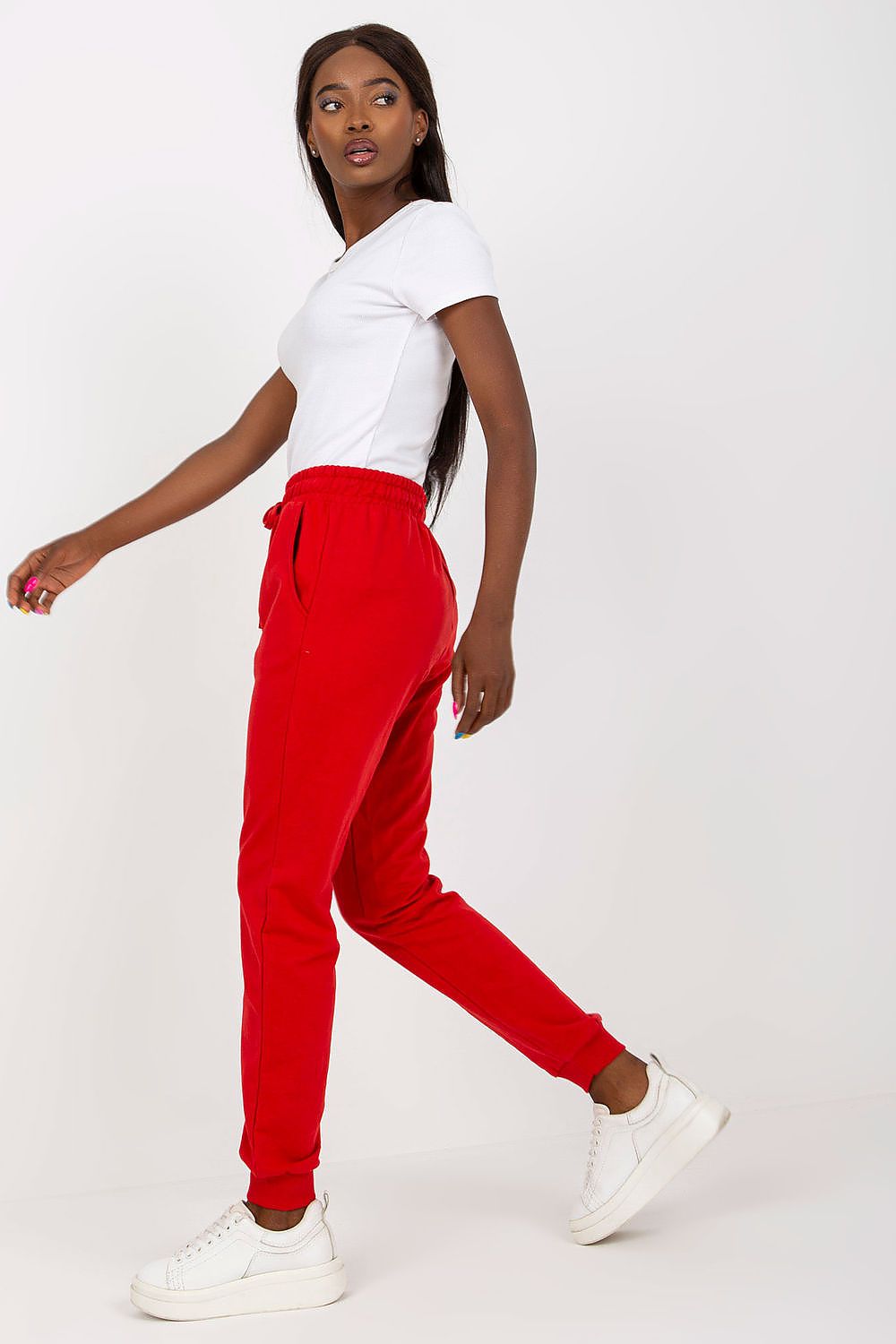 Chic pose of a model wearing red BFG high-waisted sweatpants, featuring an elastic waistband and side pockets, highlighting contemporary fashion in an elegant manner.