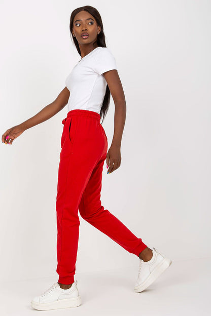 Chic pose of a model wearing red BFG high-waisted sweatpants, featuring an elastic waistband and side pockets, highlighting contemporary fashion in an elegant manner.