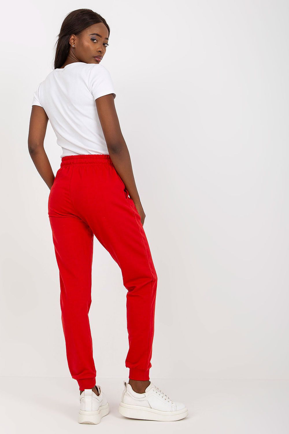 Sophisticated side view of a model in BFG red high-waisted sweatpants with elastic waistband and side pockets, accentuating modern streetwear style.