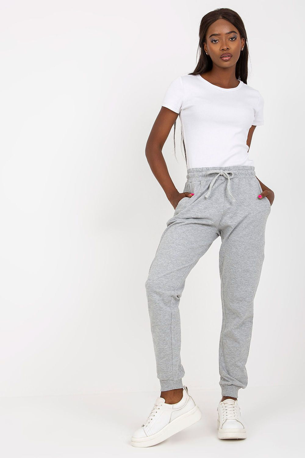 Fashion-forward model sporting BFG high-waisted sweatpants in grey, featuring an elastic waistband and side pockets, exuding luxury in a relaxed setting.