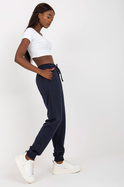 Model showcasing BFG High-Waisted Sweatpants with Elastic Waistband and Side Pockets, styled with a white crop top and trendy white sneakers, presenting a luxurious and sporty look.