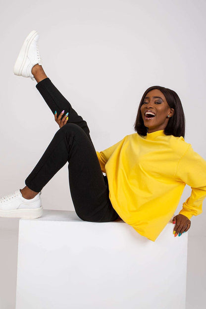 Luxury Women's Cotton Sweatshirt with Stand-Up Collar - Breathable Comfort & Style. Model playfully posing in a bright yellow sweat, styled with black trousers, radiating joy and style.