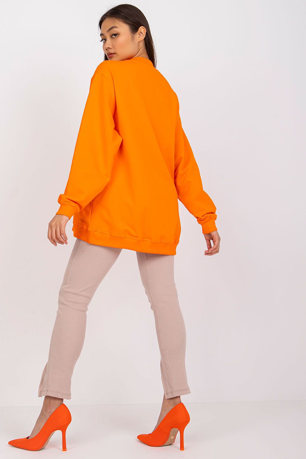 Luxury Women's Cotton Sweatshirt with Stand-Up Collar - Breathable Comfort & Style. Back view of a model in a vibrant orange sweatshirt, showcasing a chic silhouette with beige trousers.