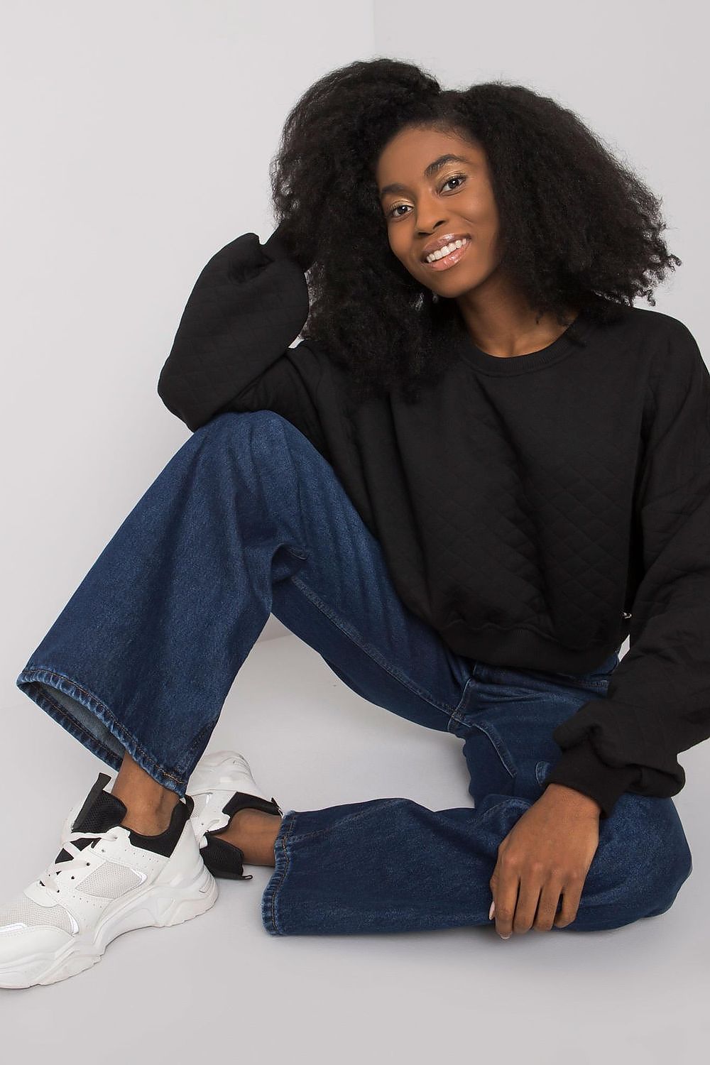 Elegant BFG Quilted Fabric Sweatshirt with Ribbed Hem – Long Sleeves, Perfect for Casual Chic. A stylish model seated in a black quilted sweatshirt, ideal for contemporary casual elegance.